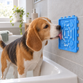 Cane che lecca il tappetino da leccare Fiuto fissato alla parete della vasca durante il bagno